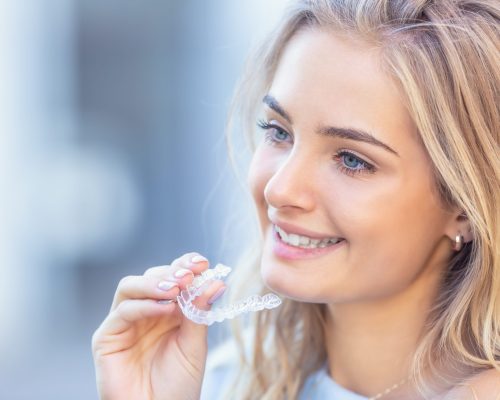 Invisalign,Orthodontics,Concept,-,Young,Attractive,Woman,Holding,-,Using Invisalign,Orthodontics,Concept,-,Young,Attractive,Woman,Holding,-,Using